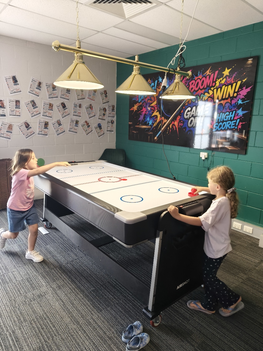 Two girls playing an energetic game of air hockey in The Pulse games room on Open Day