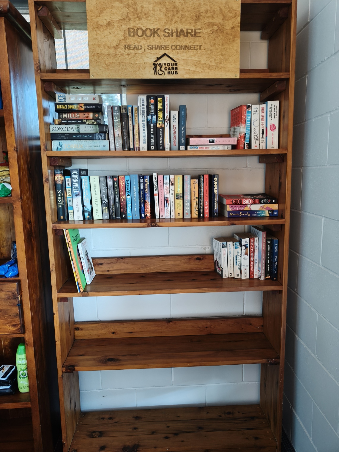 The wooden Book Share shelf filled with donated books for the community to take and leave